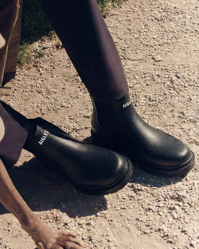 Noir coloured Aigle Chelsea Rain Ankle Boots on soil background #colour_noir