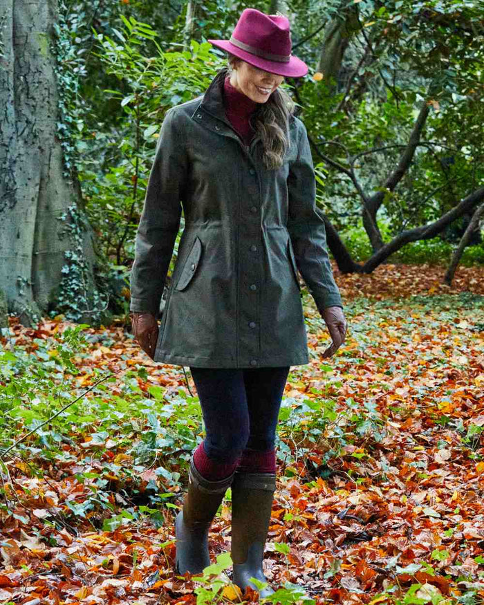 Olive coloured Alan Paine Dunswell Ladies Jacket on forest background #colour_olive