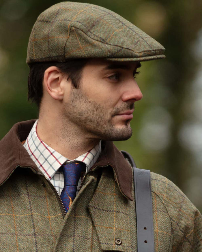 Dark Moss coloured Alan Paine Rutland Waterproof Tweed Shooting Coat on forest background #colour_dark-moss