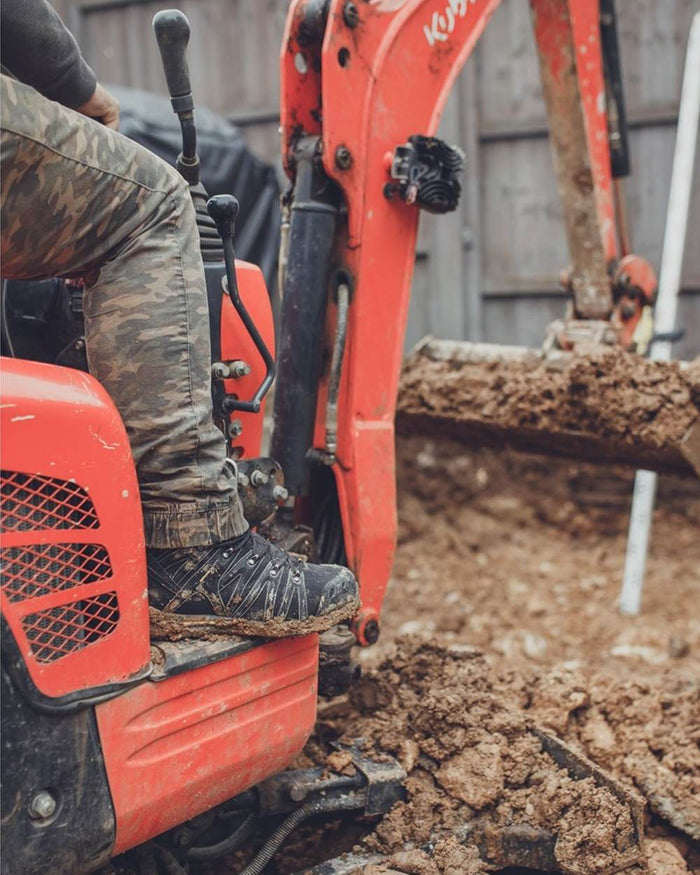 Black Coloured Amblers Safety AS254 Safety Boots on a muddy background #colour_black