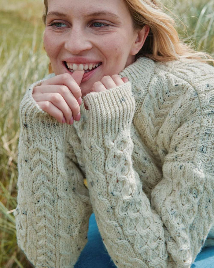 Flecked Cream coloured Aran Inishbofin Traditional Sweater on hillside background #colour_flecked-cream