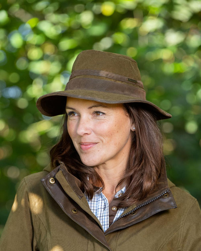 Pine Green Coloured Baleno Edith Waterproof Hat on blurry background #colour_pine-green