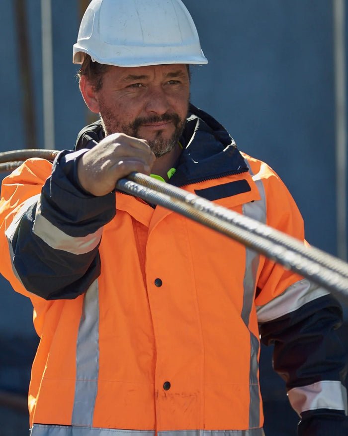 Fluoro Orange Navy coloured Betacraft ISO940 Waterproof Ranger Parka on factory background #colour_fluoro-orange-navy