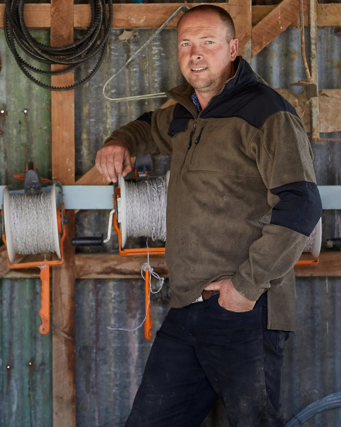 Olive coloured Betacraft Quest Eco Fleece Half Zip Top on factory background #colour_olive