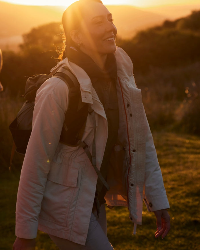 Stone coloured Craghoppers Womens NosiLife Adventure Jacket II on forest background #colour_stone