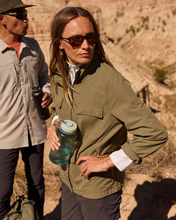 Wild Olive coloured Craghoppers Womens NosiLife Farah Jacket on mountain background #colour_wild-olive
