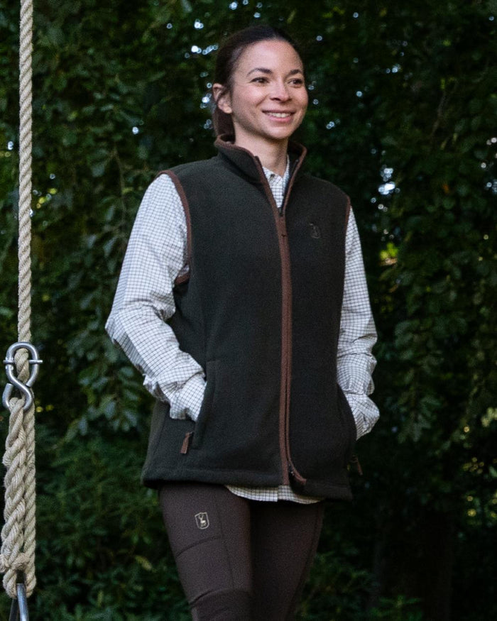 Forest Ember Coloured Deerhunter Lady Cumbria Fleece Waistcoat on forest background #colour_forest-ember