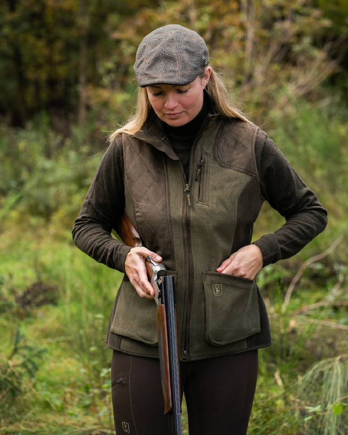 Graphite Green coloured Deerhunter Lady Pam Shooting Waistcoat on forest background #colour_graphite-green