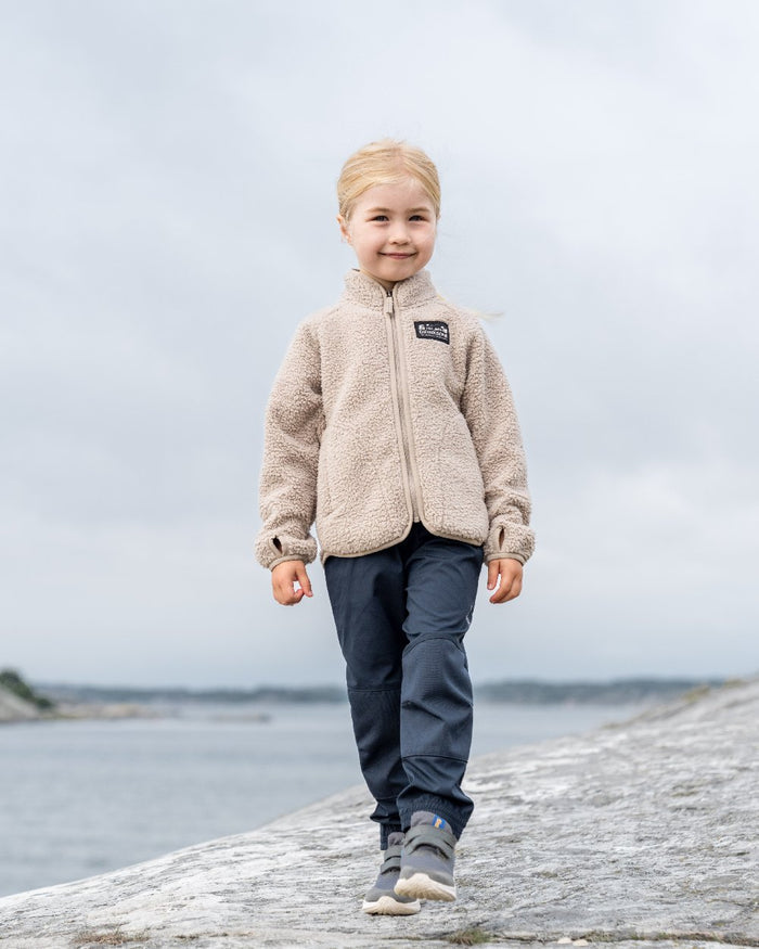 Beach Beige coloured Didriksons Childrens Gibbs Full Zip Jacket 2 on coastal background #colour_beach-beige