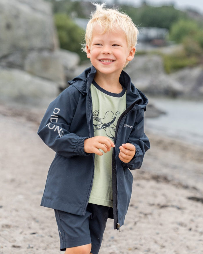 Navy coloured Didriksons Childrens Hallon Jacket on beach background #colour_navy