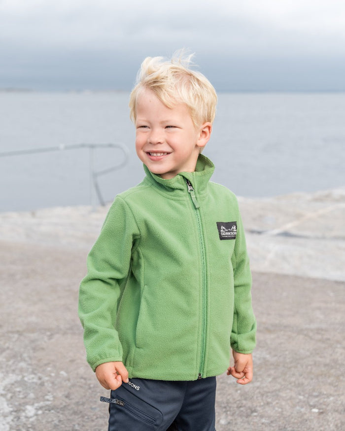 Algae Green coloured Didriksons Childrens Muskot Jacket on blurry background #colour_algae-green