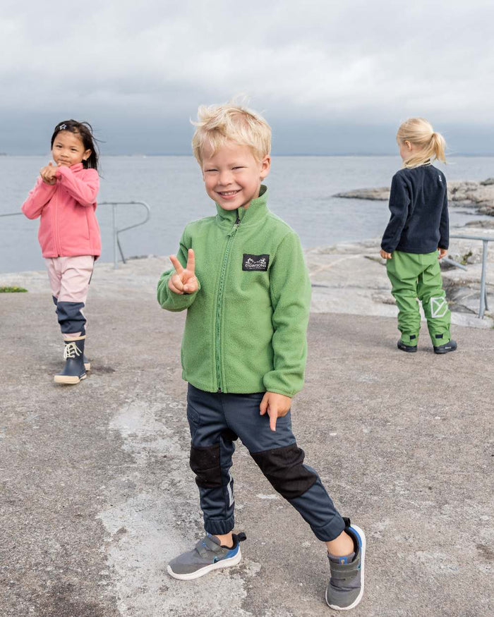 Algae Green coloured Didriksons Childrens Muskot Jacket on coastal background #colour_algae-green