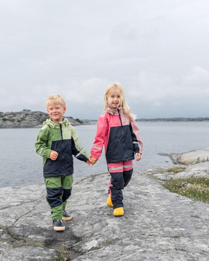 Soft Pink coloured Didriksons Childrens Pilvi Jacket on coastal background #colour_soft-pink