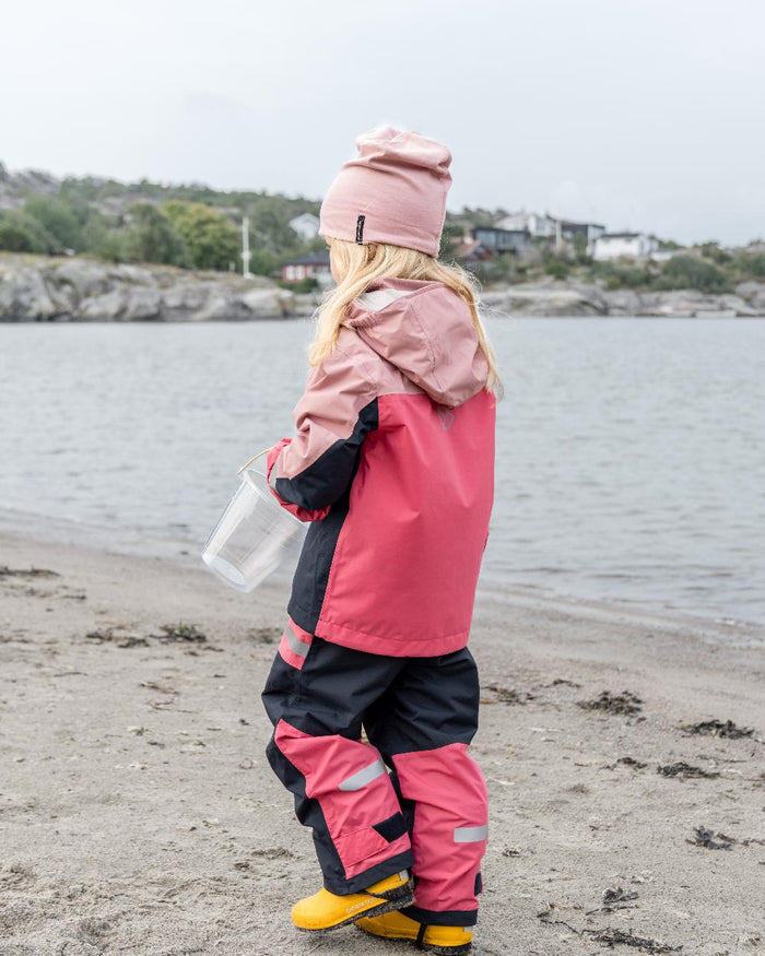 Soft Pink coloured Didriksons Childrens Pilvi Jacket on coastal background #colour_soft-pink