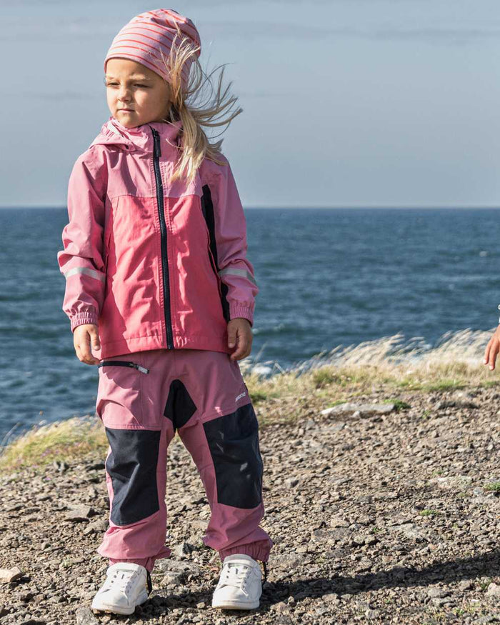 Heather Pink coloured Didriksons Childrens Pilvi Waterproof Jacket on sea background #colour_heather-pink