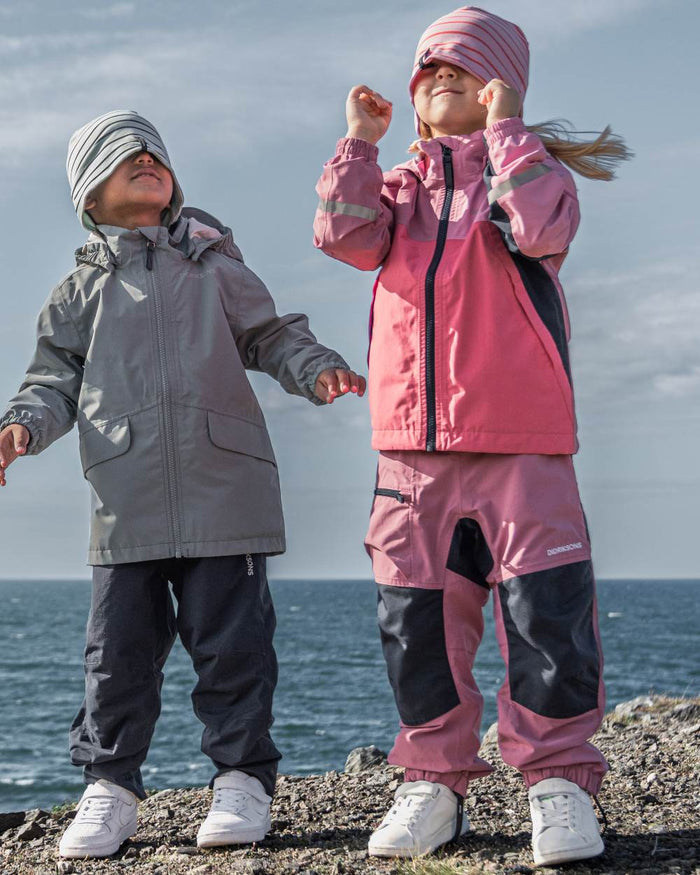 Heather Pink coloured Didriksons Childrens Pilvi Waterproof Jacket on sea background #colour_heather-pink