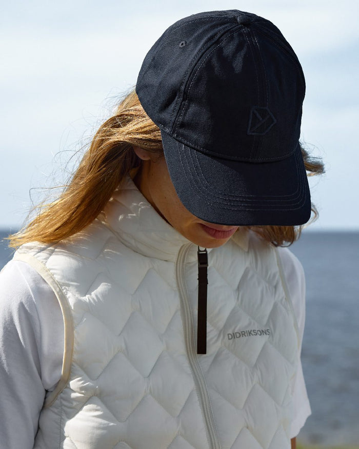Dark Night Blue coloured Didriksons Derin Cap 2 on sea background #colour_dark-night-blue