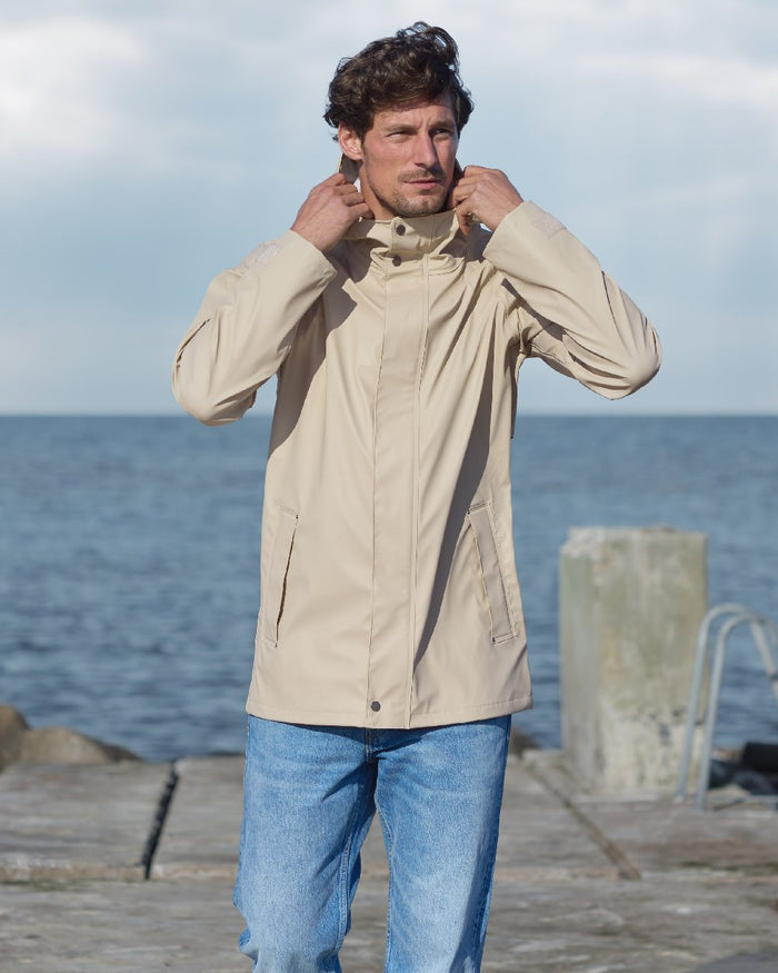 Clay Beige coloured Didriksons Mens Darwin Jacket on sea background #colour_clay-beige