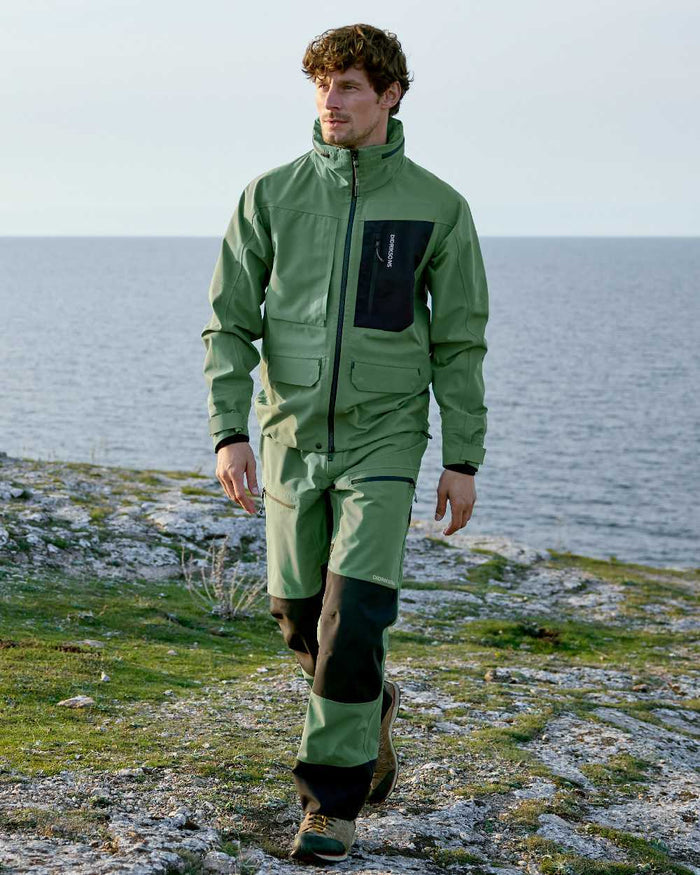 Dark Moss coloured Didriksons Mens Fractus Pants on sea background #colour_dark-moss