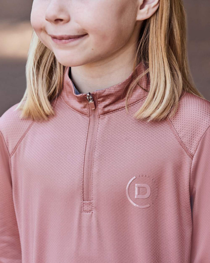 Dusty Rose coloured Dublin Kids Breathable Long Sleeve Riding Top on blurry background #colour_dusty-rose