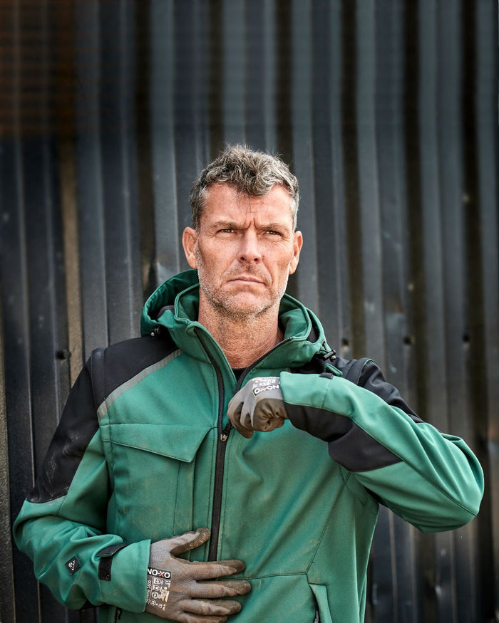 Green Black Coloured Elka Mens Working Xtreme Softshell Jacket With Detachable Sleeves on blurry background #colour_green-black