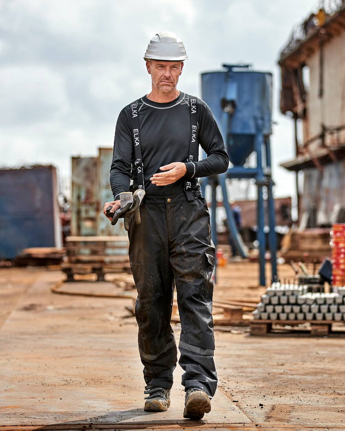 Black Coloured Elka Mens Working Xtreme Stretch Combi Trousers on construction background #colour_black