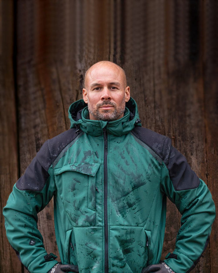 Green Black Coloured Elka Mens Working Xtreme Winter Softshell Jacket on blurry background #colour_green-black