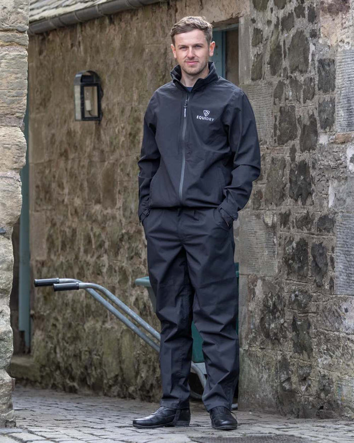 Black coloured Equidry Mens Nimbus Pack Away Jacket With Stowaway Hood on outdoor background #colour_black