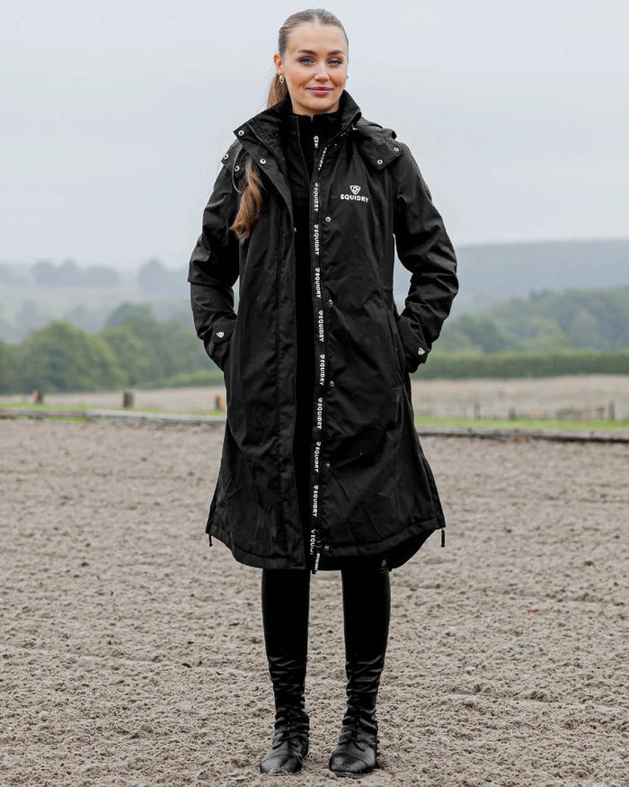 Black Coloured Equidry Womens Bronte Riding Coat With Removable Hood on outdoor background #hood_removable #colour_black