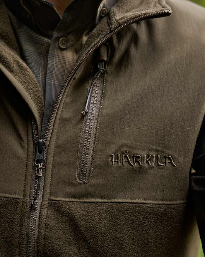 Hunting Green Willow Green Coloured Harkila Fjell Fleece Waistcoat on blurry background #colour_hunting-green-willow-green