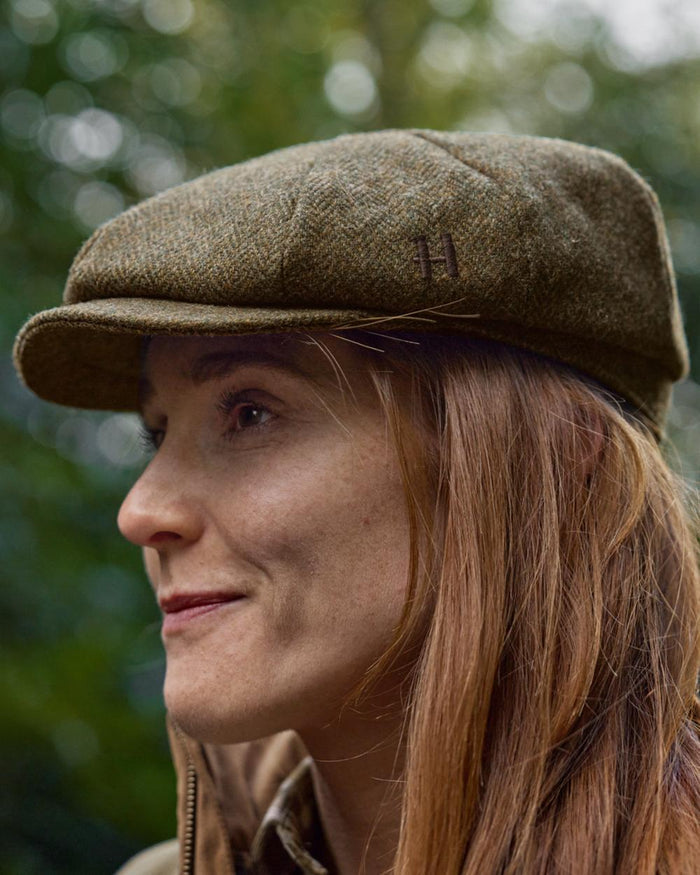Forest Green Herringbone Coloured Harkila Kenmore Classic Baker Boy Cap on forest background #colour_forest-green-herringbone