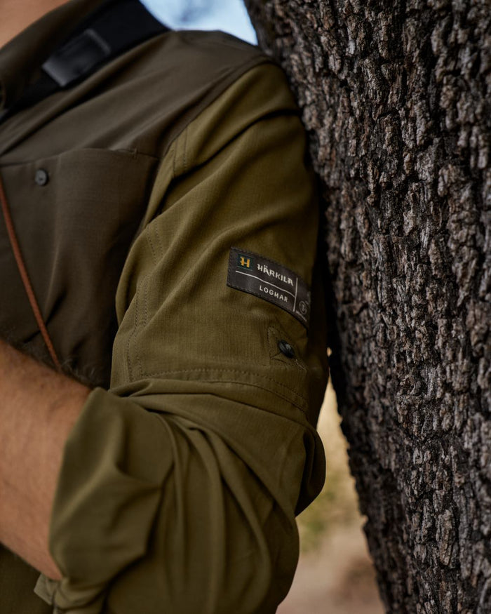 Dark Olive Willow Green Coloured Harkila Kenmore Cl. Flat Cap on forest background #colour_dark-olive-willow-green