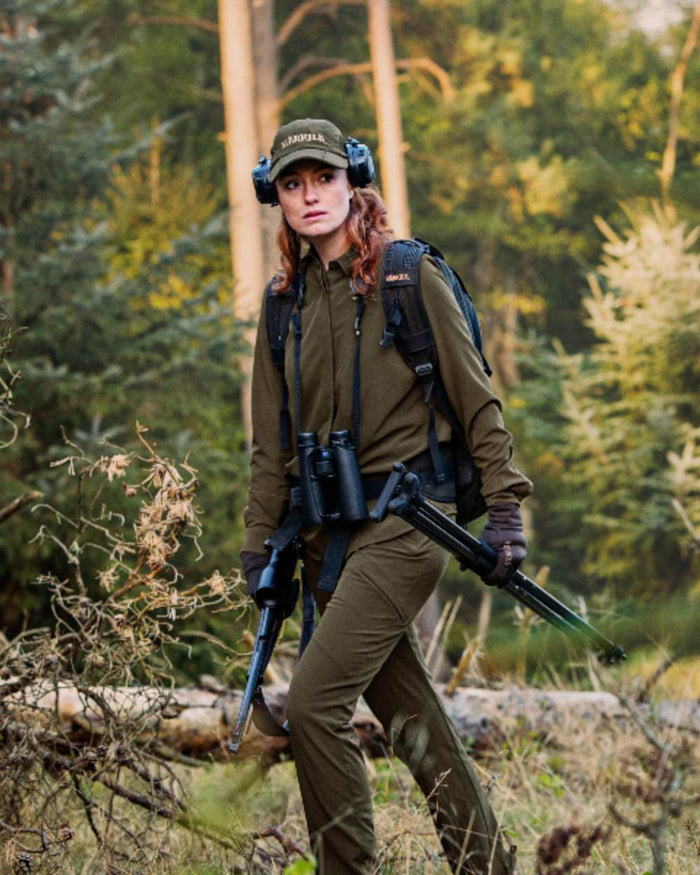 Willow Green Coloured Harkila Womens Herlet Tech Shirt on forest background #colour_willow-green
