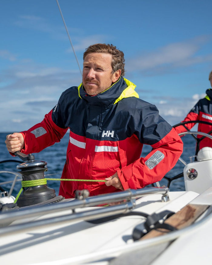Red coloured Helly Hansen Mens Pier 4.0 Jacket on blurry background #colour_red