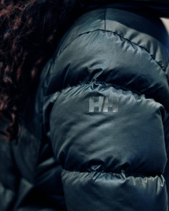 Black Coloured Helly Hansen Womens Essence Down Jacket on blurry background #colour_black
