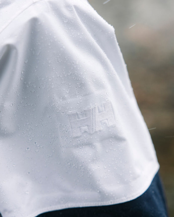 White coloured Helly Hansen Womens Koster Raincoat on blurry background #colour_white