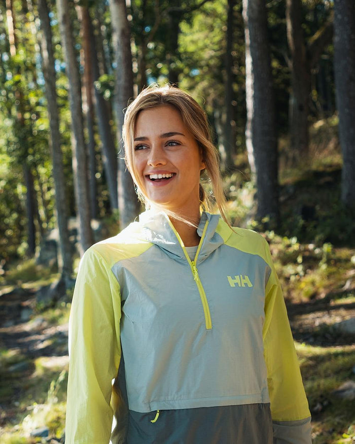 Sharp Green coloured Helly Hansen Womens Roam Wind Anorak on forest background #colour_sharp-green