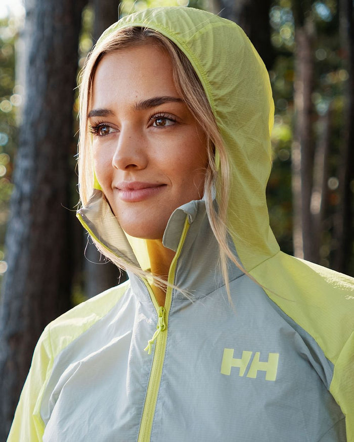 Sharp Green coloured Helly Hansen Womens Roam Wind Anorak on blurry background #colour_sharp-green