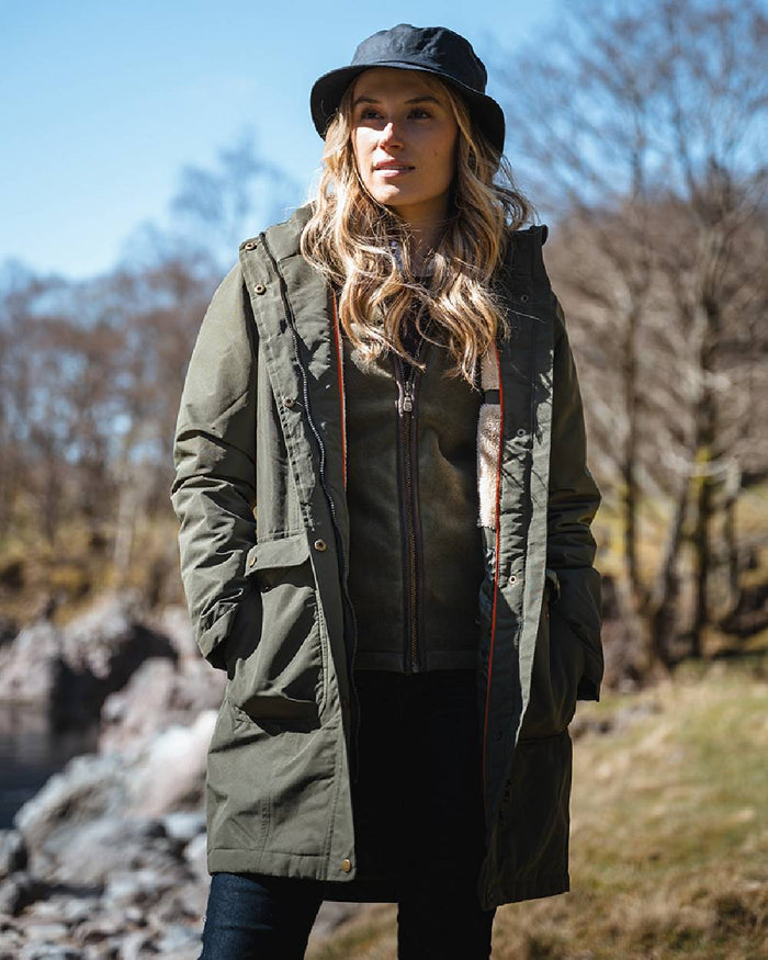 Green coloured Hoggs of Fife Womens Walker Long Coat on forest background #colour_green