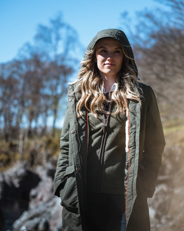 Green coloured Hoggs of Fife Womens Walker Long Coat on forest background #colour_green