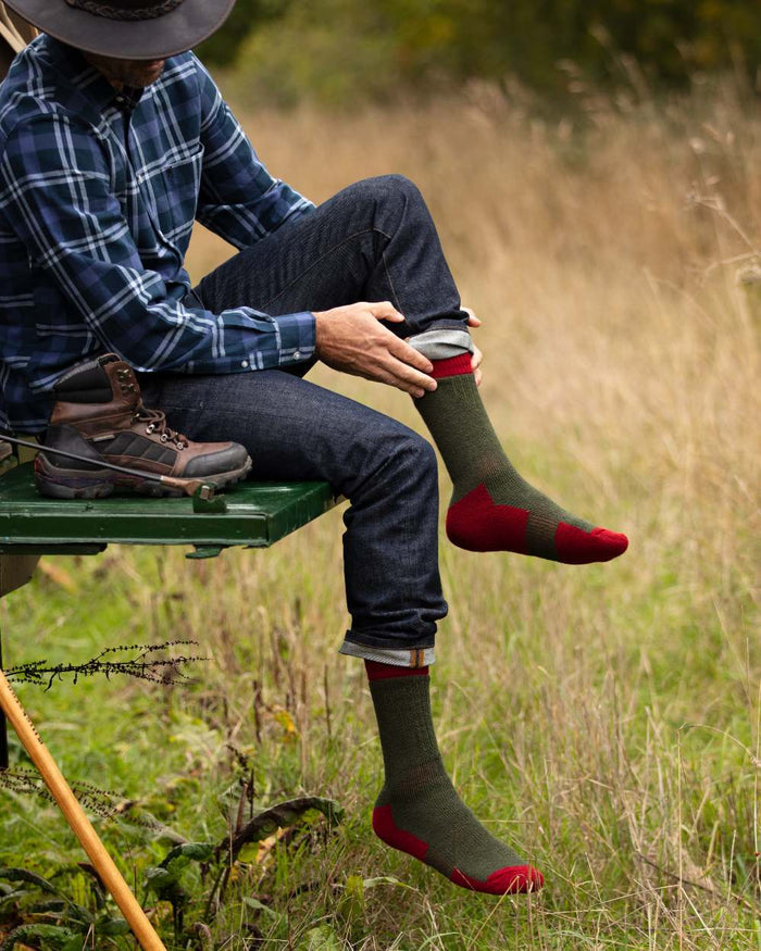 Spruce Brick Red coloured House of Cheviot Glen Technical Socks on field background #colour_spruce-brick-red