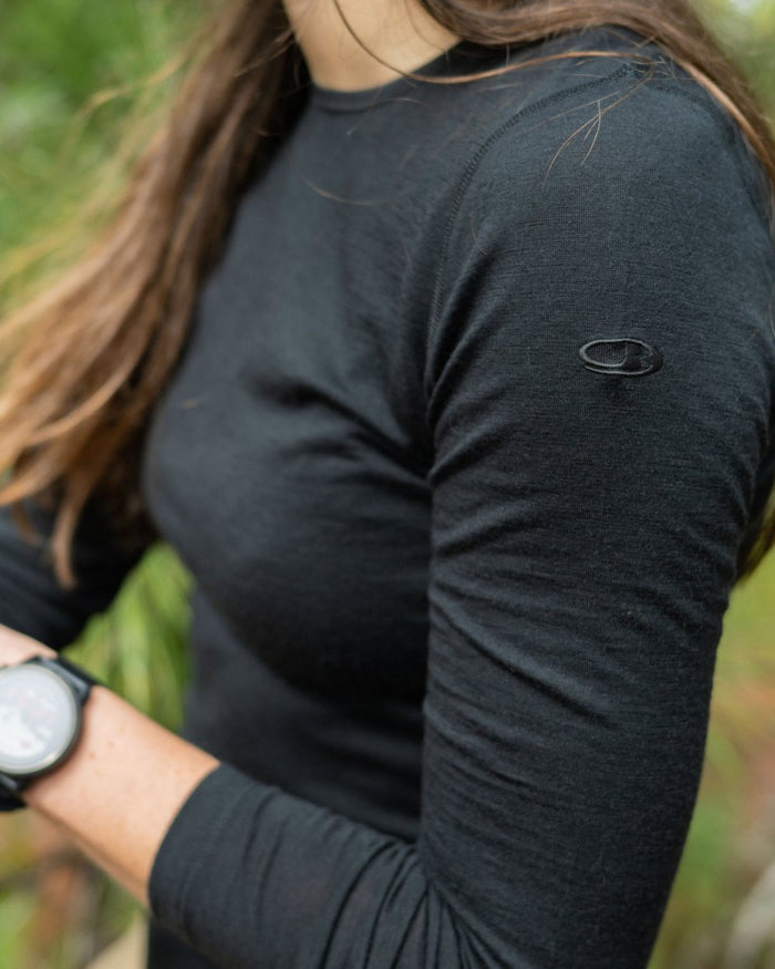 Black Coloured Icebreaker Womens Merino 200 Oasis Crewe Thermal Top on forest background #colour_black