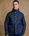 Navy coloured Jack Murphy Ronan Quilted Jacket on wall background #colour_navy