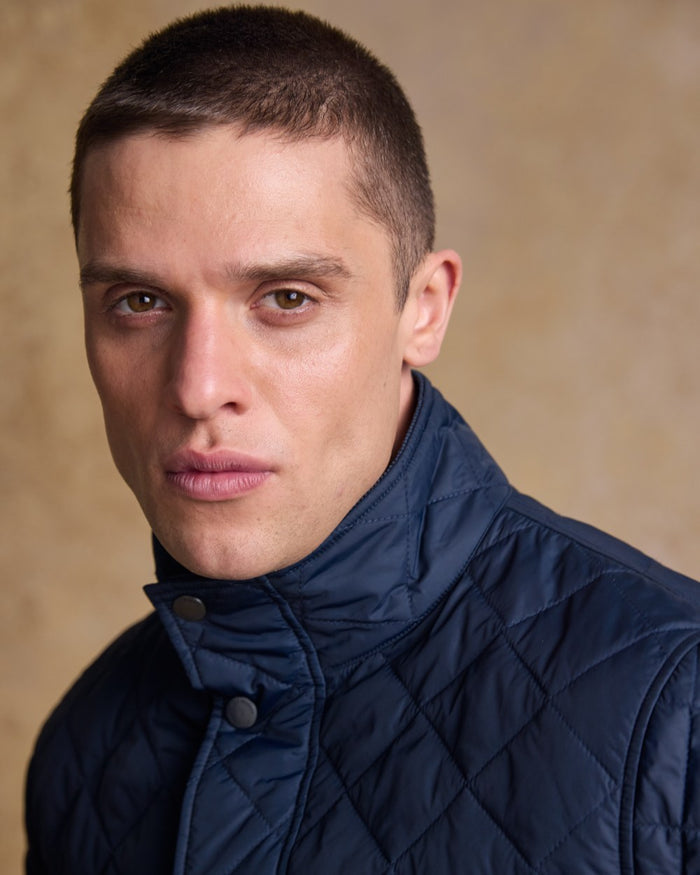 Navy coloured Jack Murphy Ronan Quilted Jacket on wall background #colour_navy