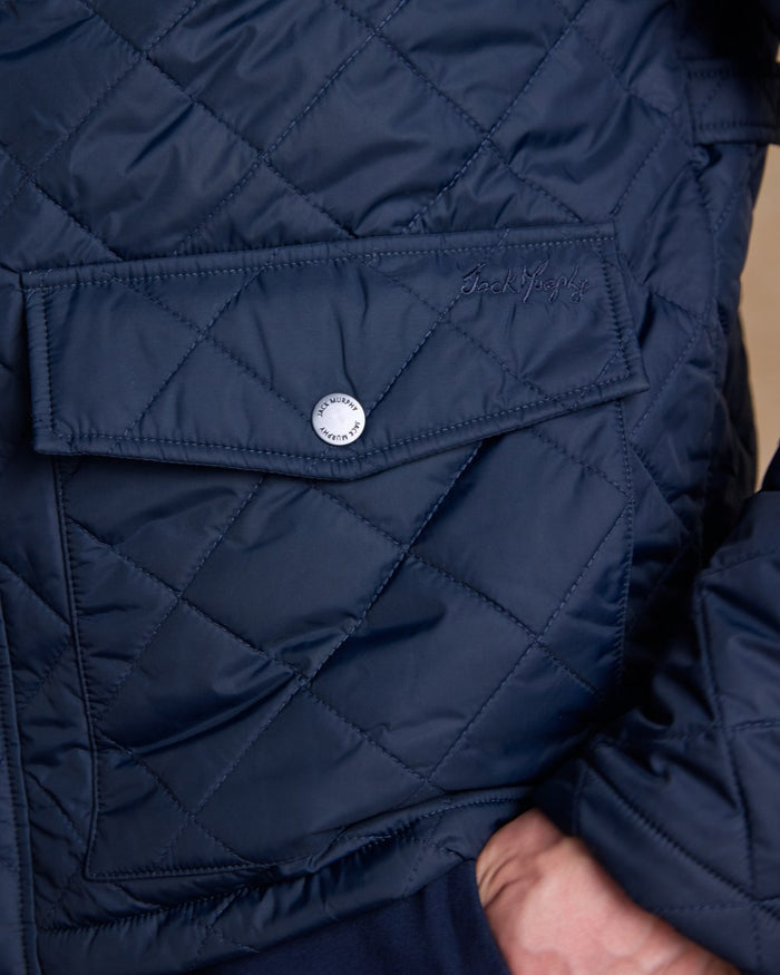Navy coloured Jack Murphy Ronan Quilted Jacket on wall background #colour_navy