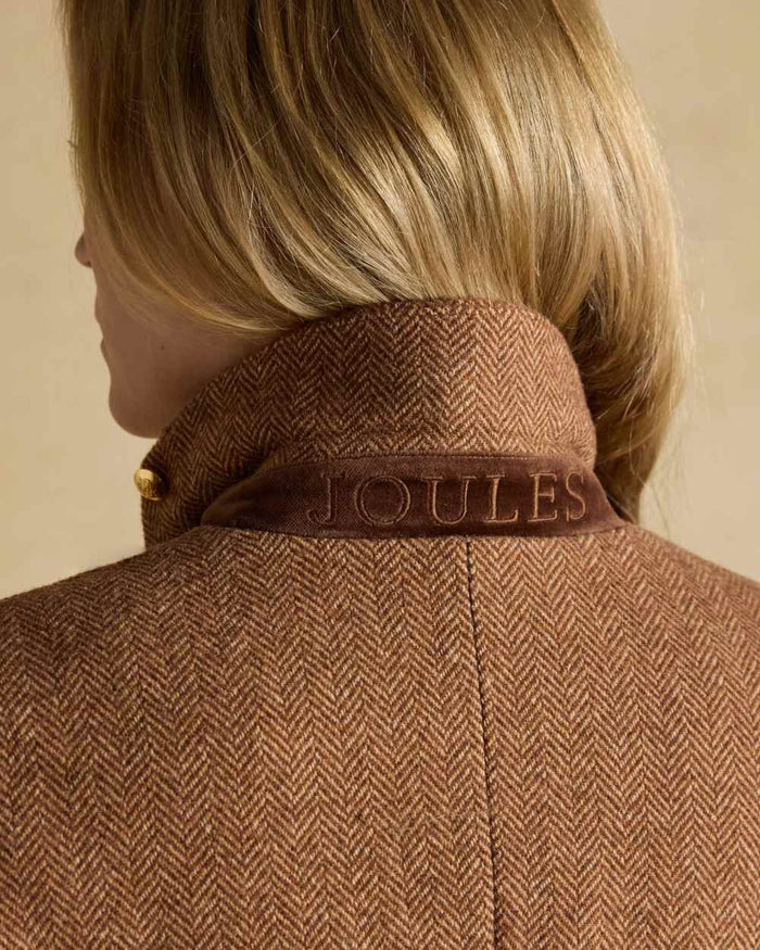 Brown Herringbone coloured Joules Womens Canterly Tweed Hacking Jacket on wall background #colour_brown-herringbone