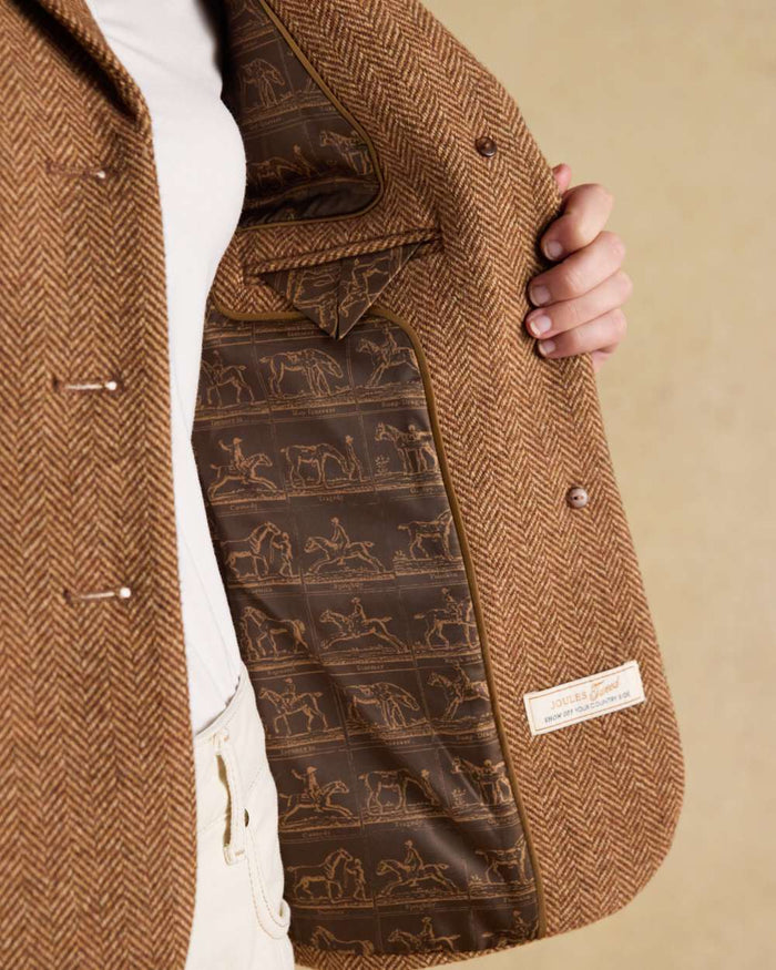 Brown Herringbone coloured Joules Womens Canterly Tweed Hacking Jacket on wall background #colour_brown-herringbone