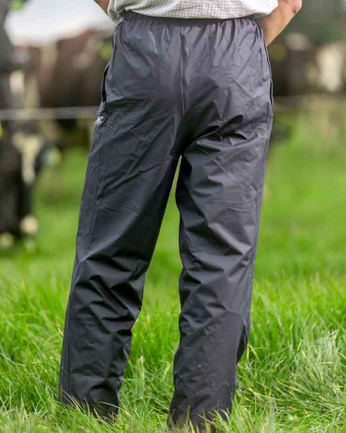 Navy coloured Kaiwaka Mens AgTex Overtrousers on grassy background #colour_navy