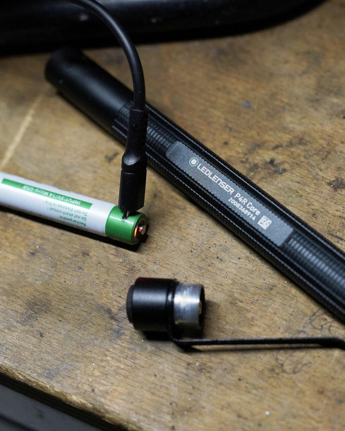 Black coloured Led Lenser P4R Core Rechargeable Torch on wooden table background #colour_black