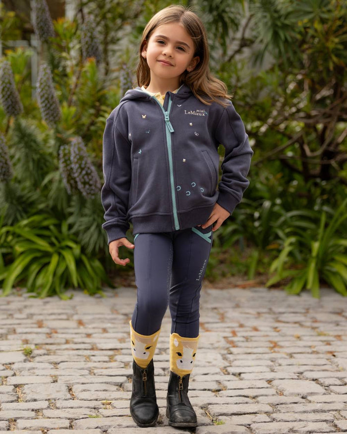 Dusk Blue coloured LeMieux Childrens Mini Charlie Zip Through Hoodie on backyard background #colour_dusk-blue